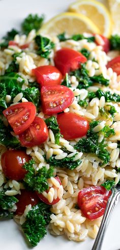 pasta salad with tomatoes, broccoli and spinach on a white platter