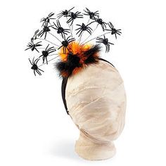 a white mannequin head with black and orange spider decorations on it's top