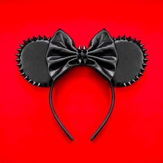 a mickey mouse ears with a black bow on it's head, against a red background