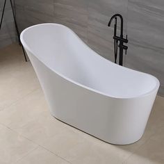 a white bathtub sitting on top of a tiled floor next to a black faucet