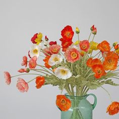 a green vase filled with lots of colorful flowers