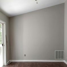 an empty room with hard wood floors and white paint on the walls, in front of a sliding glass door