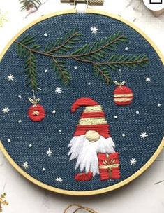 an embroidered christmas ornament with santa clause and ornaments hanging from it's hoop