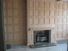 an empty room with a fireplace and wooden paneling