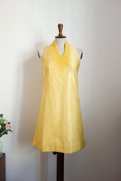 This yellow eye-catcher comes from New York and has an A-line cut. It closes in the back with a zip and a hook. The mini dress was embroidered all over with matching colored beads on the stand-up collar and around the neckline, using the finest handwork. The dress has an inner lining. The fabric is a little faded on the shoulder seam. There are two, barely noticeable, small discolorations on the back. Bust 78 cm Waist 76 cm (relatively tight for a size 34) Hips 88cm Length 85cm Garments are meas Embellished Sleeveless Yellow Dress, Yellow Embellished Sleeveless Dress, Sleeveless Yellow Embellished Dress, Yellow Embellished Dress For Summer, Yellow A-line Mini Dress For Cocktail, Twiggy Dress, A Line Cut, Yellow Eyes, Dress Clothes For Women