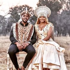 a man and woman sitting on a chair in front of trees wearing fancy costumes with feathers