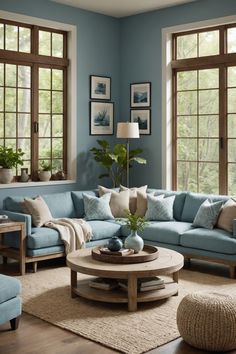 a living room with blue couches and pillows on the floor in front of large windows