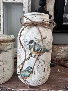 two painted jars sitting on top of a wooden table next to an old window frame