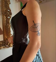 a woman with a tattoo on her arm is looking at herself in front of a mirror