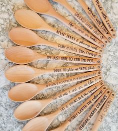 six wooden spoons with writing on them sitting on top of a granite countertop