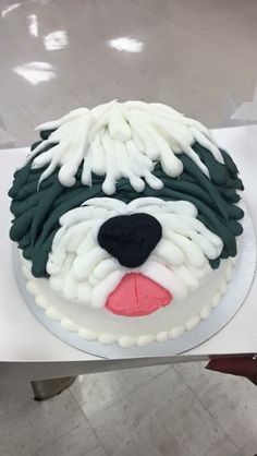 a cake with white icing and green frosting on it's face is shaped like a dog