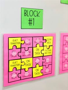 three pieces of pink and yellow puzzle on a white wall with green stickers attached to it