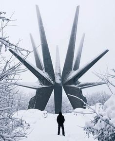 a man standing in the snow next to a large sculpture that looks like an antelope