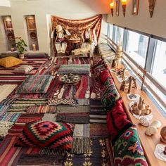 a room filled with lots of colorful rugs on top of a wooden floor next to a window