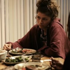 a woman sitting at a table with plates of food