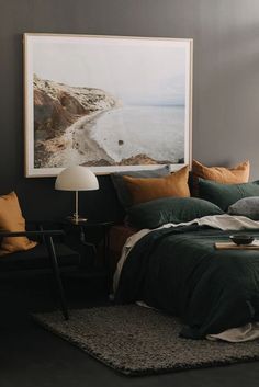 a bed with green sheets and pillows next to a painting on the wall above it