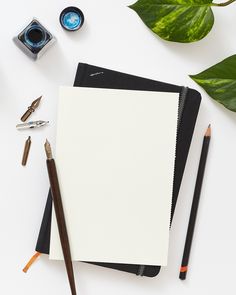 an open notepad, pencils, and other office supplies on a white surface