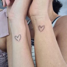 two people with matching tattoos on their arms, one holding the other's arm