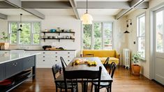 an open kitchen and dining room with white brick walls, wood flooring and black chairs