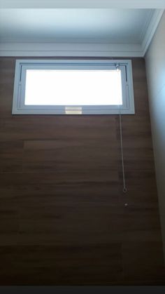 a window in the corner of a room with wood flooring and white paint on the walls