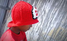 a young boy wearing a red hat with the letter e on it's brim