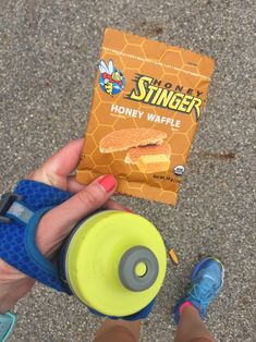 a person holding a bag of honey waffle next to a yellow and blue cup