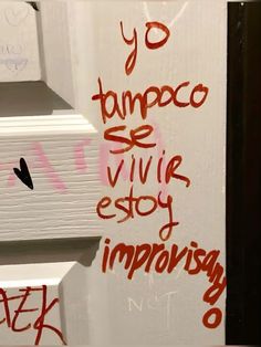 graffiti written on the side of a white door with red writing in spanish and english