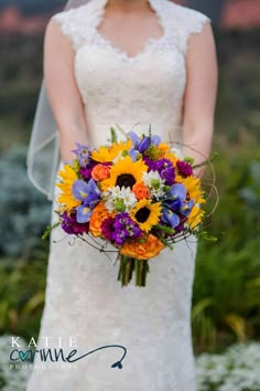 a bride holding a bouquet of sunflowers and other flowers in her wedding dress