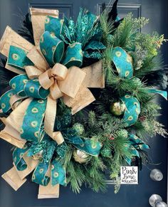 a christmas wreath with green and gold decorations hanging on a blue front door ornament