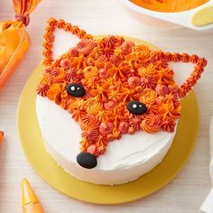 a cake decorated to look like a fox with orange icing and flowers on it