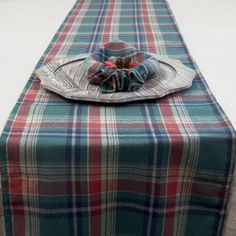 a plaid table runner with a decorative flower on the center and an empty plate at the end