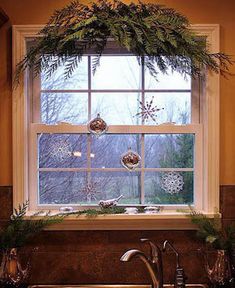 a kitchen sink under a window with christmas decorations hanging from it's windowsill