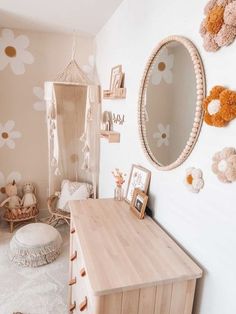 a child's room with flowers on the wall and a wooden dresser in front of it