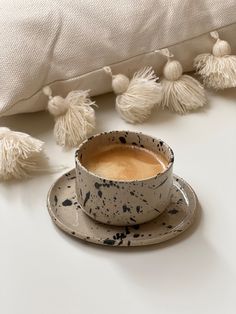 a cup of coffee sitting on top of a saucer next to a white pillow