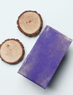 two pieces of wood are next to a purple soap bar on a white surface,