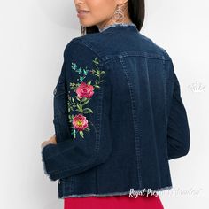 a woman wearing a denim jacket with embroidered flowers on the front and back, standing against a white wall