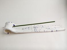 a toothbrush holder with blue speckles on it and a green toothbrush in the middle