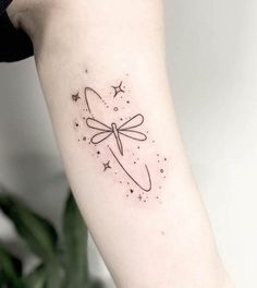 a woman's arm with a tattoo on it that has stars and a dragonfly