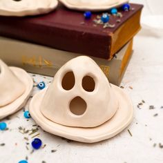 two ceramic ghost heads sitting on top of a table next to a book and some confetti