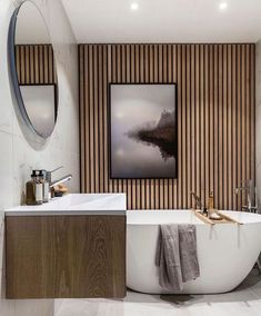 a white bath tub sitting next to a sink under a framed painting on the wall