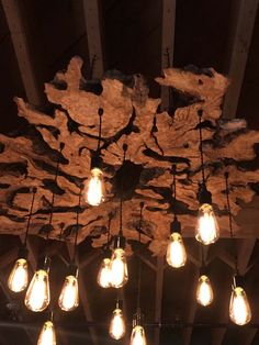 a bunch of light bulbs hanging from the ceiling in a room with wood beams and exposed lighting