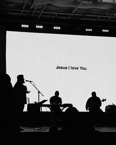 silhouettes of people playing instruments and singing in front of a large screen with the words jesus i love you