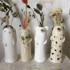 three ceramic vases with flowers and plants in them