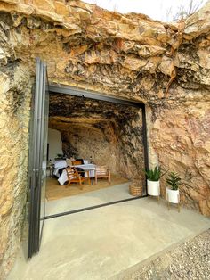 an open door leading into a cave like area with tables and chairs on the ground