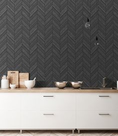 a kitchen with black and white herringbone tiles on the wall, wooden counter tops and drawers