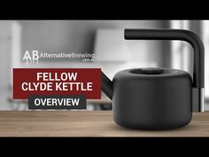 a black kettle sitting on top of a wooden table next to a red sign that says fellow clyde kettle overview