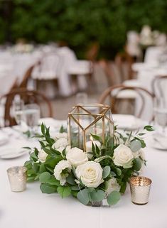 a table with white flowers and greenery is set up for a formal dinner or reception