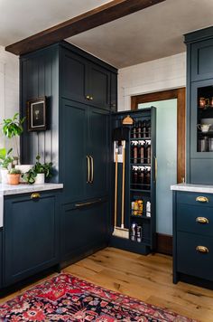 a kitchen with dark blue cabinets and white counter tops, gold pulls on the doors