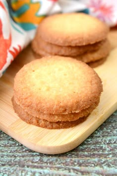 three cookies sitting on top of a wooden cutting board next to a cloth and napkin