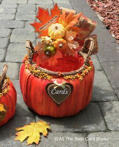 two pumpkins decorated with autumn decorations and leaves on the ground next to each other